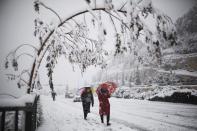 Women walk with umbrellas on a snow-covered road during winter in Jerusalem December 12, 2013. Schools and offices in Jerusalem and parts of the occupied West Bank were closed and public transport briefly suspended after heavy snowfall on Thursday. REUTERS/Amir Cohen (JERUSALEM - Tags: ENVIRONMENT)