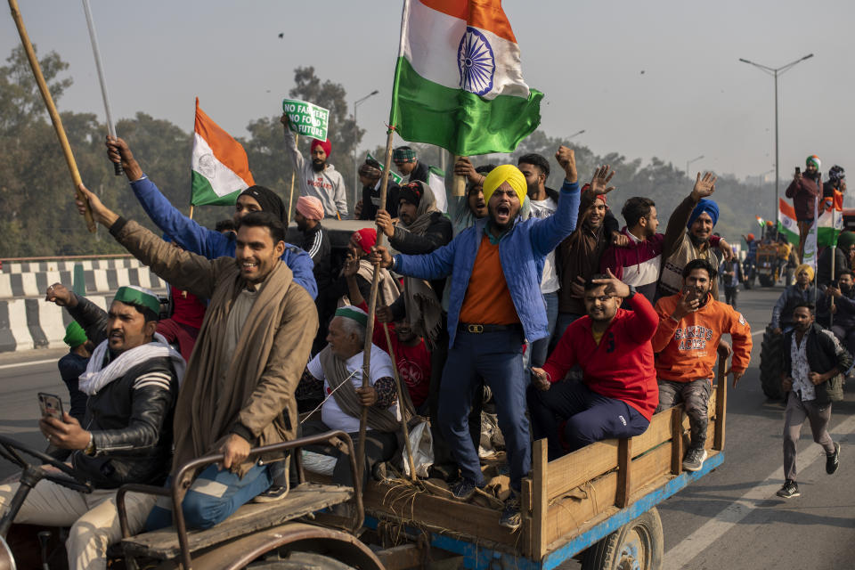 Protesting farmers riding tractors shout slogans as they march to the capital breaking police barricades during India's Republic Day celebrations in New Delhi, India, Tuesday, Jan. 26, 2021. Tens of thousands of farmers drove a convoy of tractors into the Indian capital as the nation celebrated Republic Day on Tuesday in the backdrop of agricultural protests that have grown into a rebellion and rattled the government. (AP Photo/Altaf Qadri)