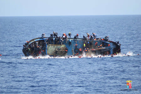 Migrants are seen on a capsizing boat before a rescue operation by Italian navy ships "Bettica" and "Bergamini" off the coast of Libya in this handout picture released by the Italian Marina Militare on May 25, 2016. Marina Militare/Handout via REUTERS