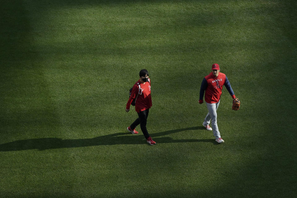 Los Angeles Angels starting pitcher Shohei Ohtani, right, walks to the bullpen with Ippei Mizuhara, left, his interpreter, before the team's baseball game against the Seattle Mariners, Thursday, June 16, 2022, in Seattle. (AP Photo/Ted S. Warren)