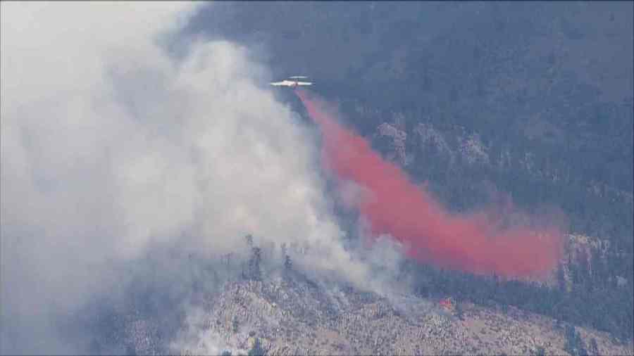 A firefighting plane drops fire retardant on visible flames from the Alexander Mountain Fire, as seen from SkyFOX on July 29, 2024.