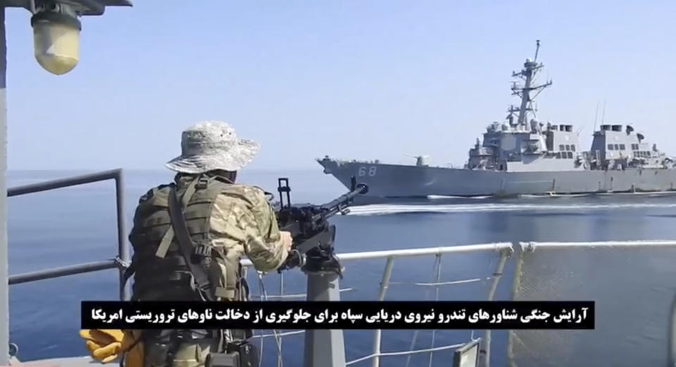 This frame grab from a video released by Iran's paramilitary Revolutionary Guard on Wednesday, Nov. 3, 2021, shows a Guard soldier on a speed boat in front of a U.S warship amid the seizure of a Vietnamese-flagged oil tanker in the Gulf of Oman. Iran seized the tanker in the Gulf of Oman last month and still holds the vessel, two U.S. officials told The Associated Press on Wednesday, revealing the latest provocation in Mideast waters as tensions escalate between Iran and the United States over Tehran's nuclear program. (Revolutionary Guard via AP)