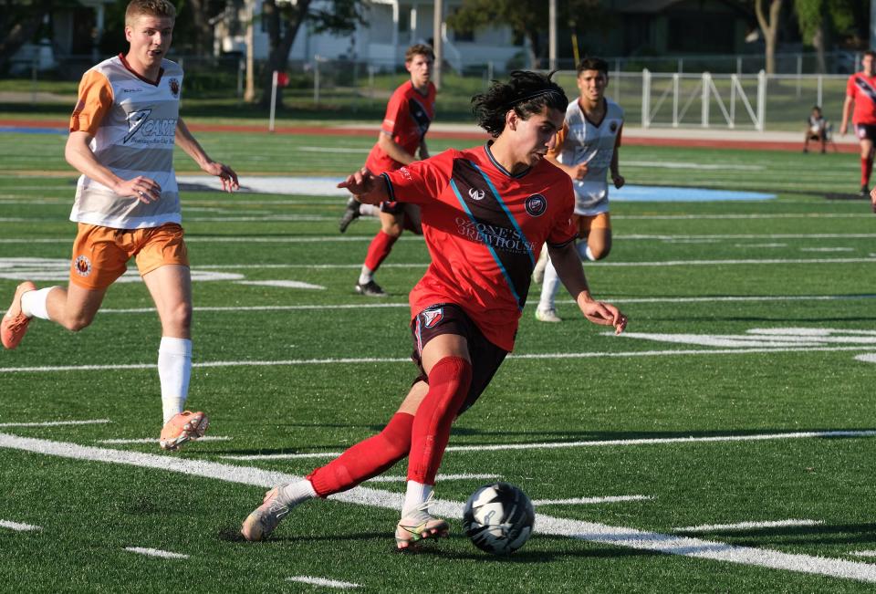 Lansing Common player Munir Sherali moves the ball upfield in the team's inaugural game at Lansing Eastern against West Michigan Bearings Saturday, May 22, 2021.