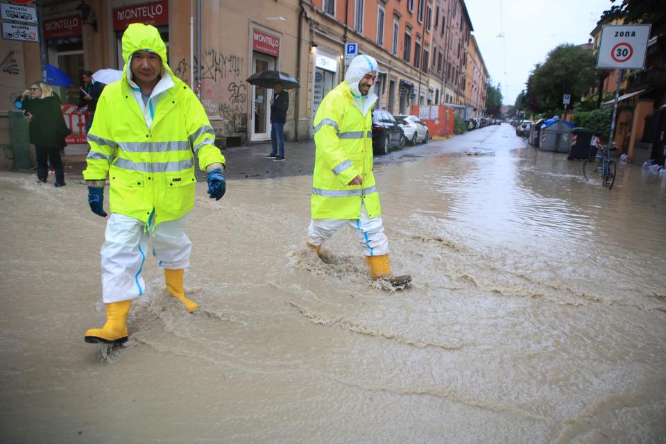 People crosses a flooded street in Bologna, Italy, Tuesday, May 16, 2023.