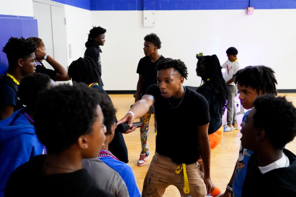 Camari Hubbard, 16, center, points a microphone to a group of kids during Rec @ Nite on June 29 at Hirsch Recreation Center in Cincinnati. The theme of the event was 513 After Dark, where a club was created in the gym.