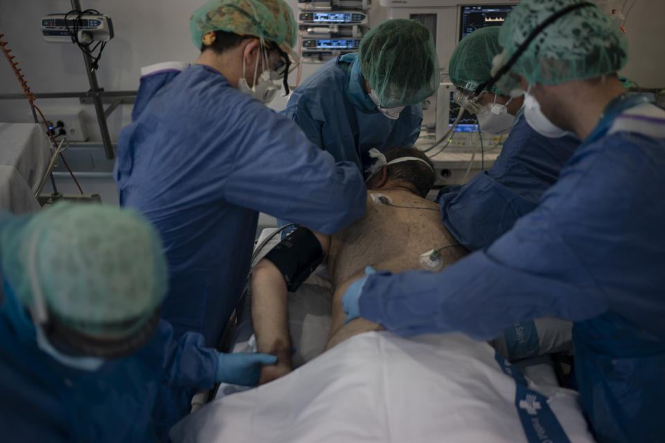 Healthcare workers assist a COVID-19 patient at a library that was turned into an intensive care unit (ICU) at Germans Trias i Pujol hospital in Badalona, Barcelona province, Spain, Wednesday, April 1, 2020. The new coronavirus causes mild or moderate symptoms for most people, but for some, especially older adults and people with existing health problems, it can cause more severe illness or death. (AP Photo/Felipe Dana)