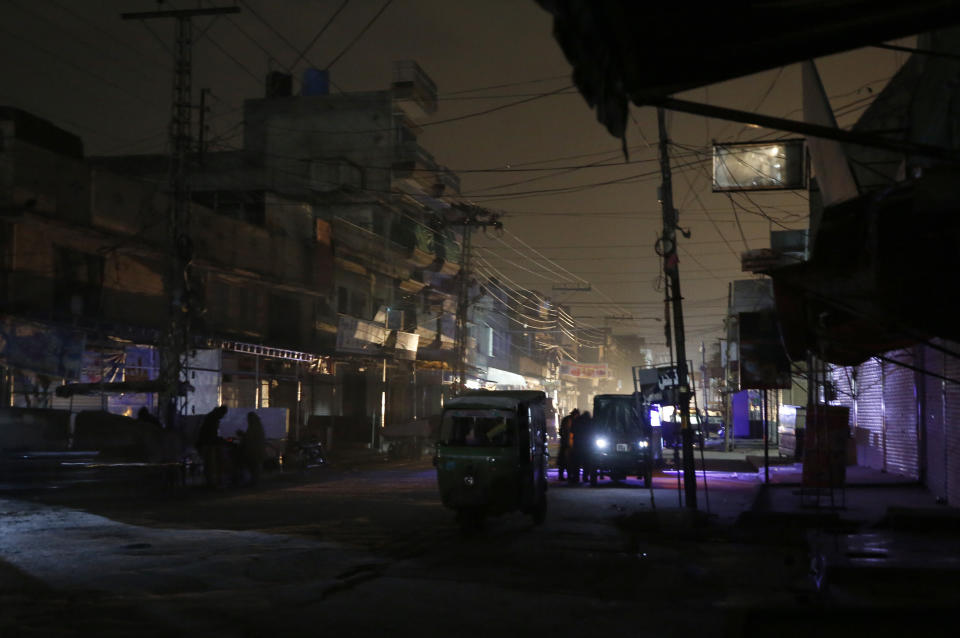 People and auto rickshaws are silhouetted on vehicles headlights on a dark street during widespread power outages in Rawalpindi, Pakistan, Sunday, Jan. 10, 2021. Pakistan's national power grid experienced a major breakdown late night on Saturday, leaving millions of people in darkness, local media reported. (AP Photo/Anjum Naveed)