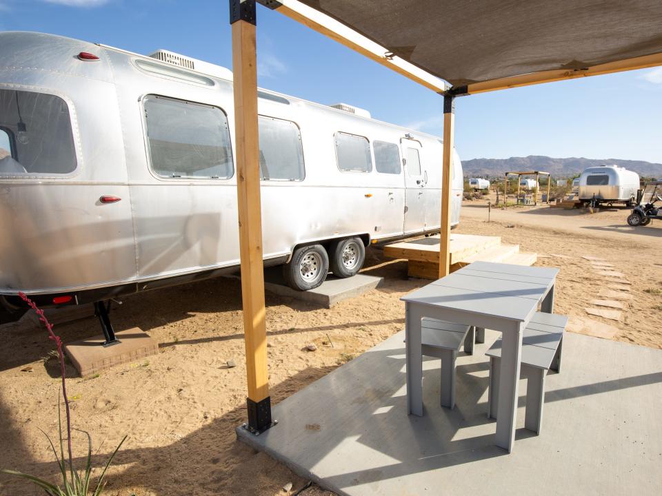 Airstream trailers with a fire pit, seating outside at Autocamp's Joshua Tree location.