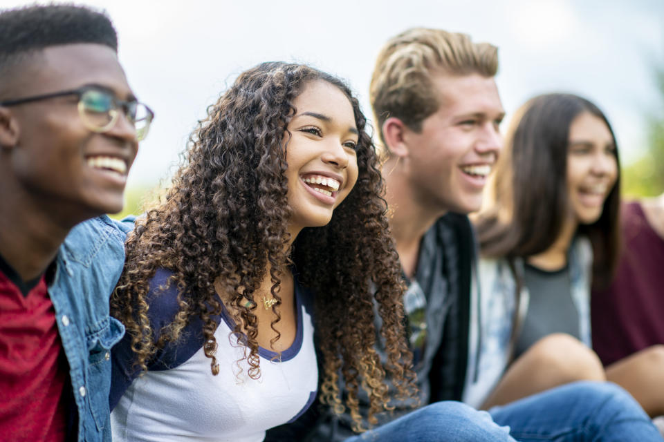 A group of young teens smiles and laughs together