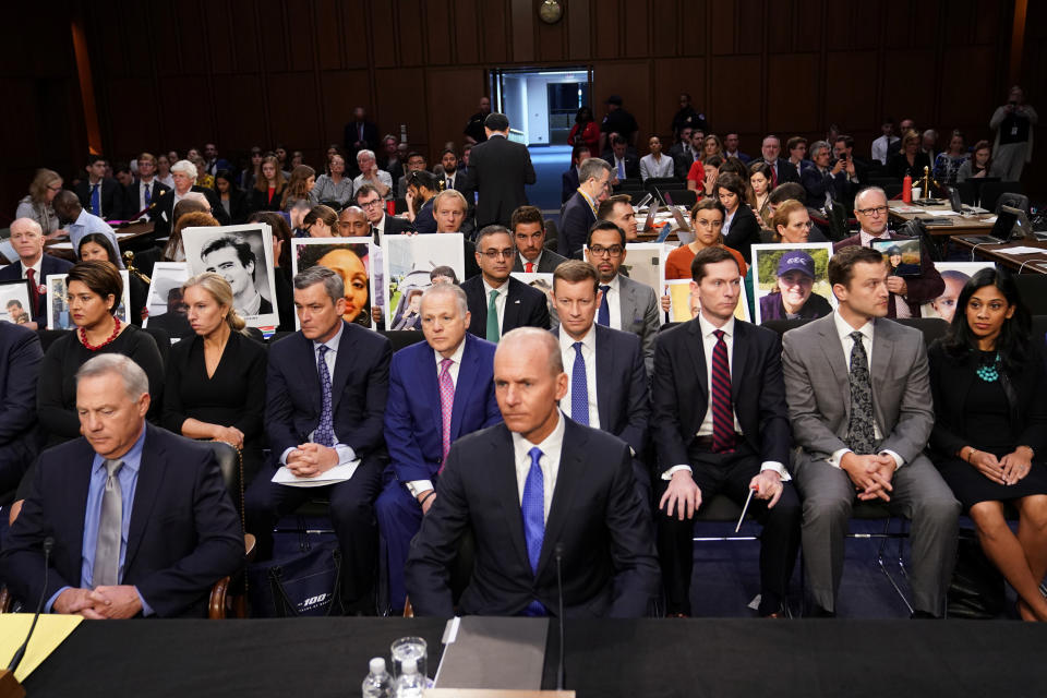 Boeing Chief Executive Dennis Muilenburg sits in front of family members holding photographs of Boeing 737 MAX crash victims from two deadly 737 MAX crashes that killed 346 people as Muilenburg waits to testify before a Senate Commerce, Science and Transportation Committee hearing on “aviation safety” and the grounded 737 MAX on Capitol Hill in Washington, U.S., October 29, 2019.  REUTERS/Sarah Silbiger