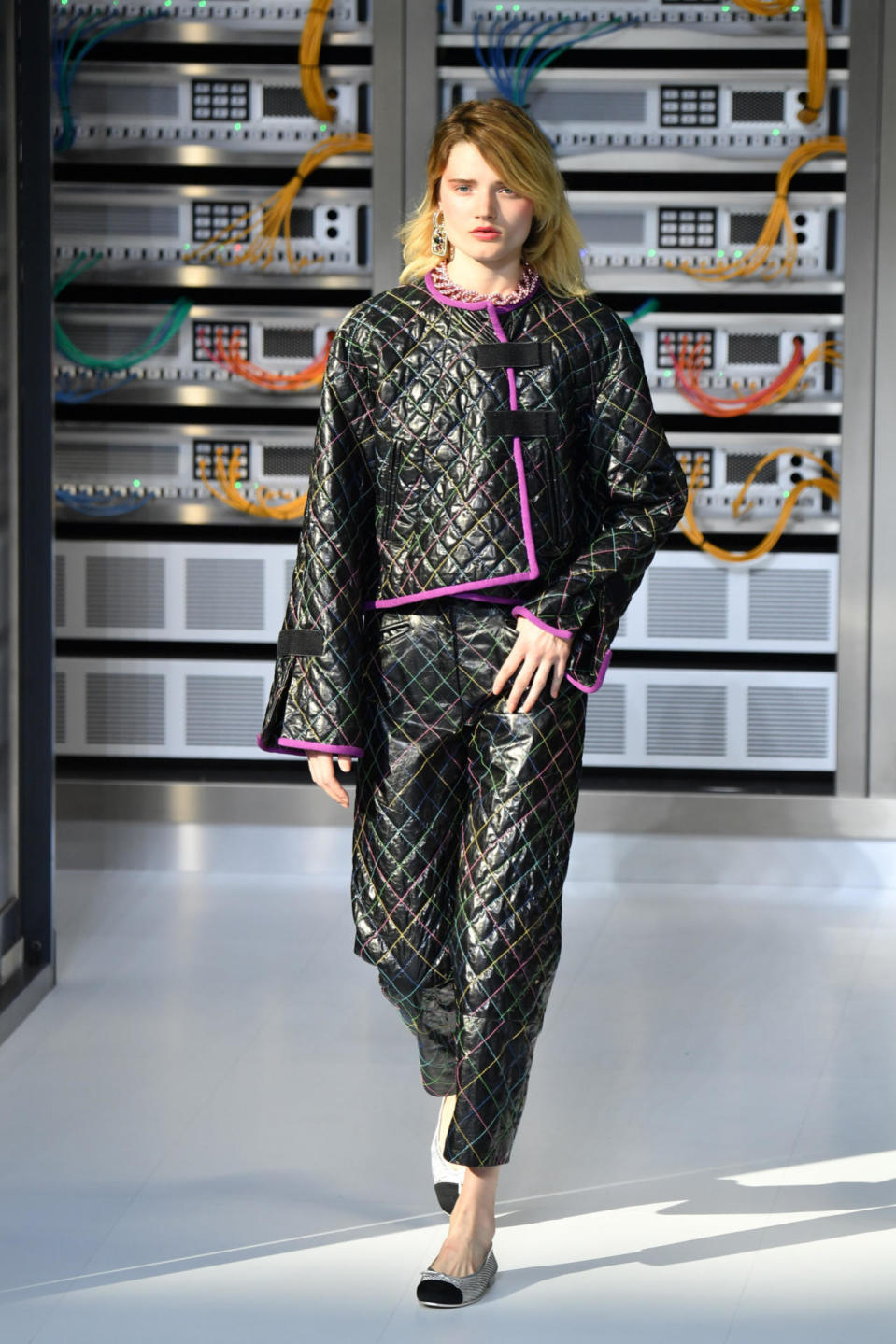 Only Chanel could make trash-bag-inspired seem so incredibly chic, as evidenced on this model in a matching quilted suit with colorful stitching. 