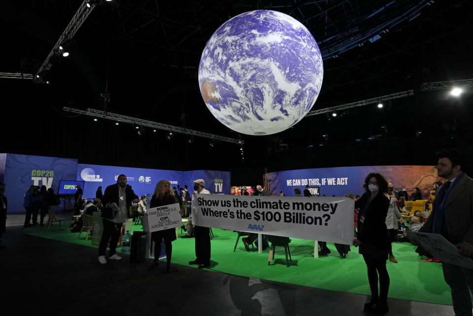 FILE - Protesters hold a sign inside the venue at the COP26 U.N. Climate Summit in Glasgow, Scotland, Nov. 5, 2021. The U.N. climate summit in Glasgow gathers leaders from around the world, in Scotland's biggest city, to lay out their vision for addressing the common challenge of global warming. (AP Photo/Alastair Grant, File)