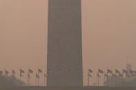 People run at the base of the Washington Monument and a thick layer of smoke covering Thursday, June 8, 2023, in Washington. Intense Canadian wildfires are blanketing the northeastern U.S. in a dystopian haze, turning the air acrid, the sky yellowish gray and prompting warnings for vulnerable populations to stay inside. (AP Photo/Jose Luis Magana)