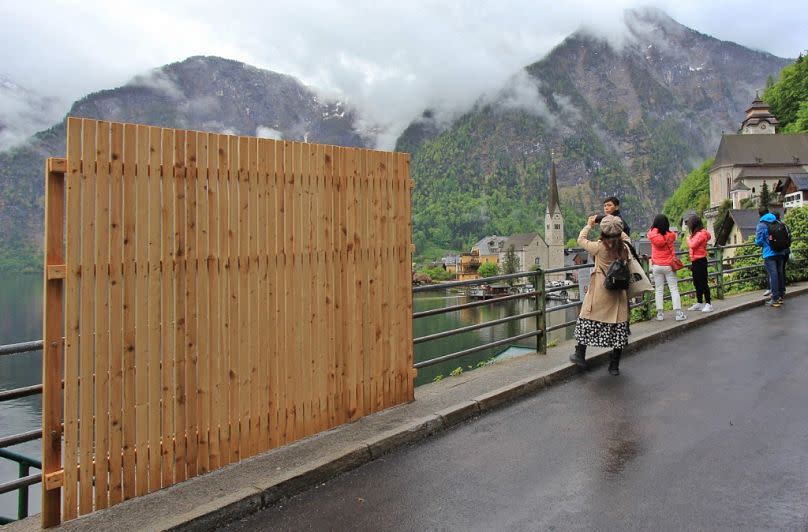 Ein provisorischer Holzzaun versperrt teilweise die schöne Aussicht, während Besucher Selfies mit der Landschaft in der Tourismusgemeinde Hallstatt machen. (Bild: REINHARD HORMANDINGER/AFP)