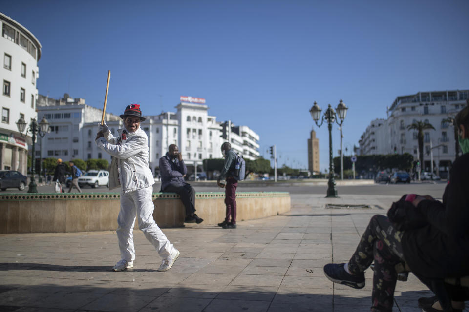 Belhussein Abdelsalam, a Charlie Chaplin impersonator performs some poses for walking pedestrians on a main avenue in Rabat, Morocco, Saturday, March 13, 2021. When 58-year-old Moroccan Belhussein Abdelsalam was arrested and lost his job three decades ago, he saw Charlie Chaplin on television and in that moment decided upon a new career: impersonating the British actor and silent movie maker remembered for his Little Tramp character. (AP Photo/Mosa'ab Elshamy)