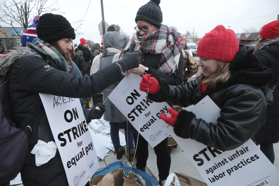 From left to right, Kathryn Schoedel, a teacher at Ziumbo Elementary School, Lindsay Anderson, a teacher at Torres Elementary school and Vanessa Cerf-Nikolakakis, a teacher at Torres Elementary School with their signs as they prepare to walk the picket line outside of Acero's Zizumbo Elementary charter school on Tuesday, Dec. 4, 2018, in Chicago. Hundreds of teachers have gone on strike at the Chicago charter school network, leading to canceled classes for thousands of students. (Antonio Perez/ Chicago Tribune via AP)