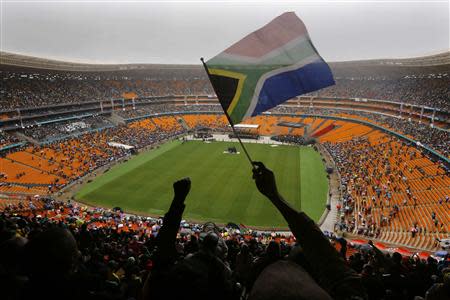 A man waves a South African flag during a memorial service for former South African President Nelson Mandela at the First National Bank (FNB) Stadium, also known as Soccer City, in Johannesburg December 10, 2013. REUTERS/Yannis Behrakis