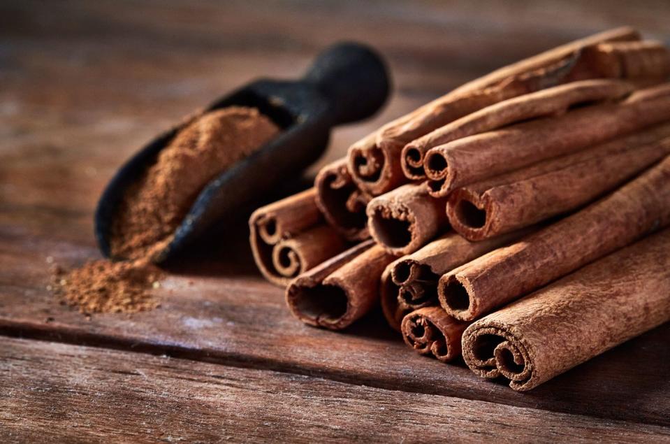 stick cinnamon and cinnamon powder on rustic wooden table with copy space