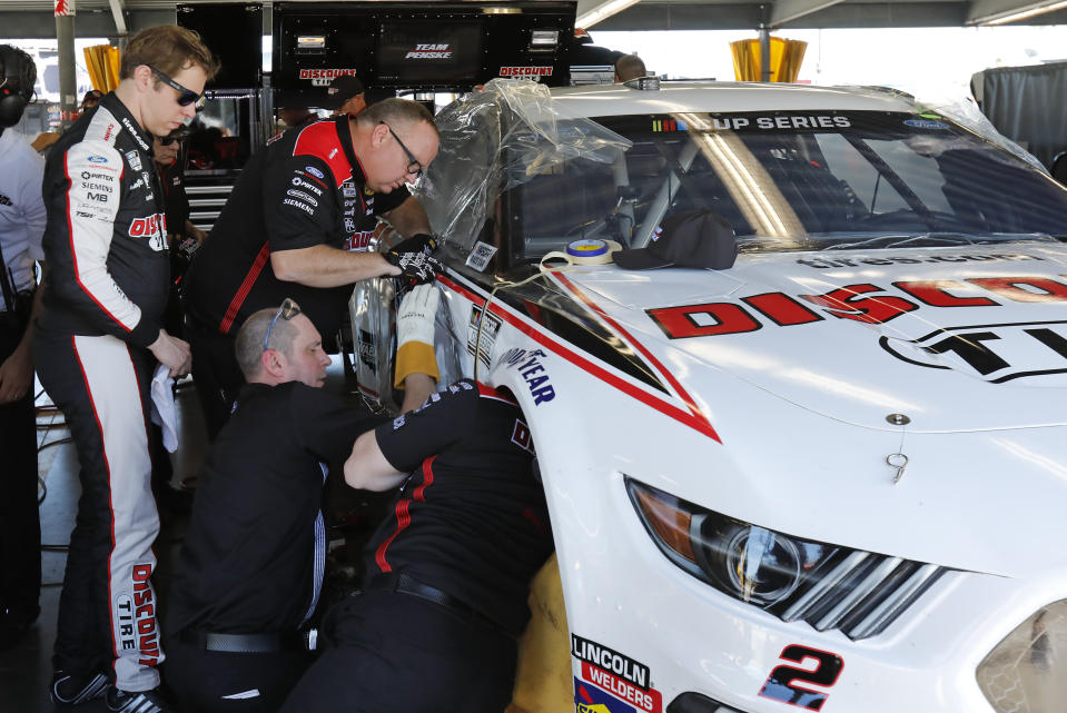 Brad Keselowski, left, looks over his car as his crew makes repairs after he wrecked during NASCAR auto race practice at Daytona International Speedway, Saturday, Feb. 8, 2020, in Daytona Beach, Fla. (AP Photo/Terry Renna)