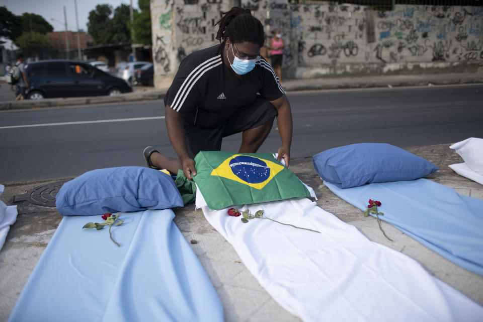 A demonstrator places a Brazil national flag on a mattress symbolizing COVID-19 victims, during a protest against the Government's handling of the COVID-19 pandemic, organized by the Rio de Paz NGO, in front of the Ronaldo Gazolla hospital in Rio de Janeiro, Brazil, Wednesday, March 24, 2021. (AP Photo/Silvia Izquierdo)