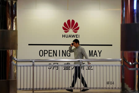 A man using his mobile phone walks past a yet-to-open Huawei store inside a shopping mall in Shanghai, China May 16, 2019. REUTERS/Aly Song