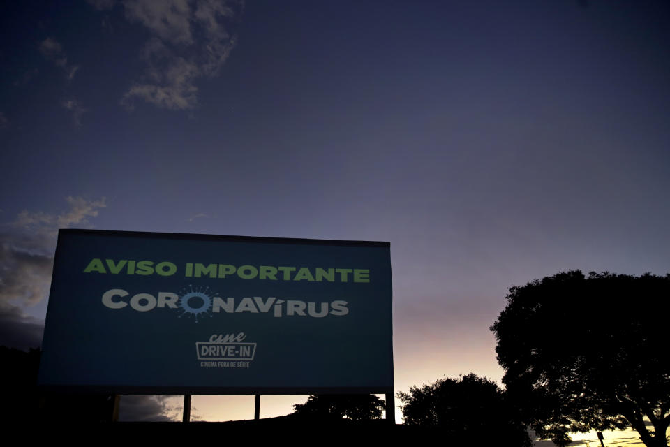 A sign that flashes different warnings about coronavirus, in Portuguese, stands tall at a drive-in movie theater where drivers must leave one space empty between them in Brasilia, Brazil, Saturday, May 23, 2020. The drive-in was closed at the start of the pandemic but reopened to the public at the start of April. (AP Photo/Eraldo Peres)