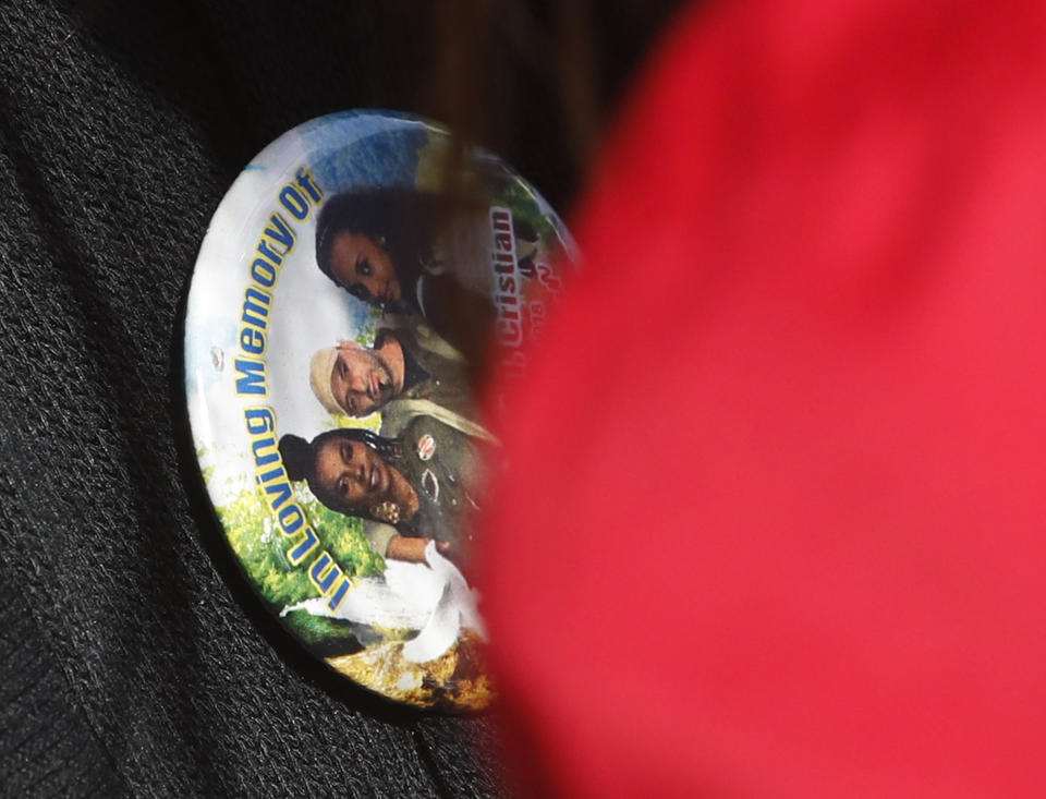A pin worn by a relative of one the victims of the Morandi bridge collapse, is framed by the red uniform of one of the rescuers that worked that day, during a remembrance ceremony to mark the first anniversary of the tragedy, in Genoa, Italy, Wednesday, Aug. 14, 2019. The Morandi bridge was a road viaduct on the A10 motorway in Genoa, that collapsed one year ago killing 43 people. (AP Photo/Antonio Calanni)