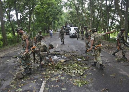 Indian army personnel remove branches of a tree which were thrown by the protesters to block the road at Golaghat district in the northeastern Indian state of Assam August 21, 2014. REUTERS/Stringer