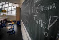 FILE -- In this Friday, March 13, 2020 photo a slogan on a chalkboard reads 'It's Corona Time' in an empty class room of a high school in Frankfurt, Germany, March 13, 2020. As Germany’s 16 states start sending millions of children back to school in the middle of the global coronavirus pandemic, those used to the country’s famous “Ordnung” are instead looking at uncertainty, with a hodgepodge of regional regulations that officials acknowledge may or may not work. (AP Photo/Michael Probst, file)