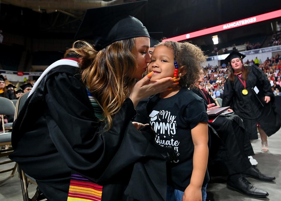 Mariah Vega of Worcester kisses her daughter, Aliana Vega-Walker, 3, after she helped her mother carry her master of arts in counseling psychology diploma during Anna Maria College's 74th commencement exercises at the DCU Center Monday.