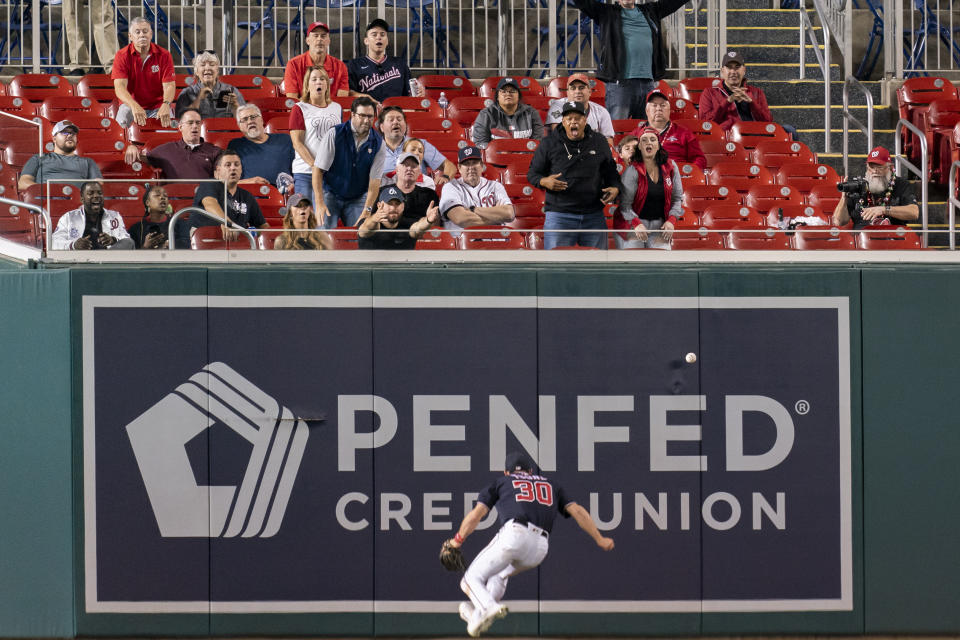 Fans react as Washington Nationals center fielder Jacob Young is unable to catch a ball hit in by Chicago White Sox's Luis Robert Jr. for a double during the ninth inning of a baseball game Tuesday, Sept. 19, 2023, in Washington. (AP Photo/Stephanie Scarbrough)