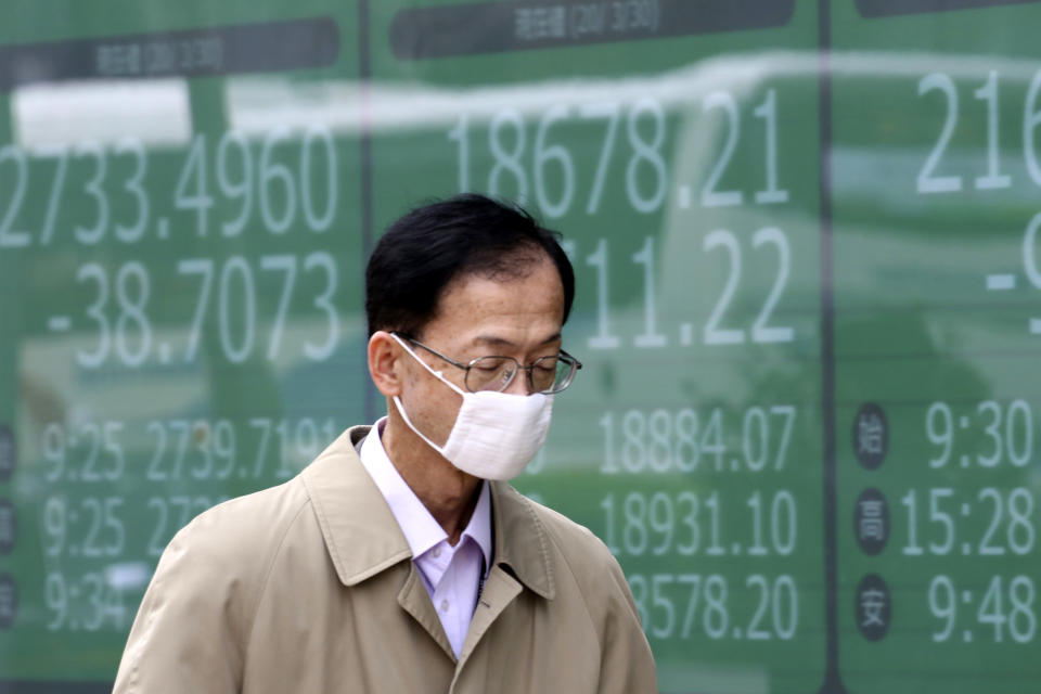 A man walks by an electronic stock board of a securities firm in Tokyo, Monday, March 30, 2020. Asian shares started the week with further losses as countries reported surging numbers of infections from the coronavirus that has prompted shutdowns of travel and business in many parts of the world.(AP Photo/Koji Sasahara)