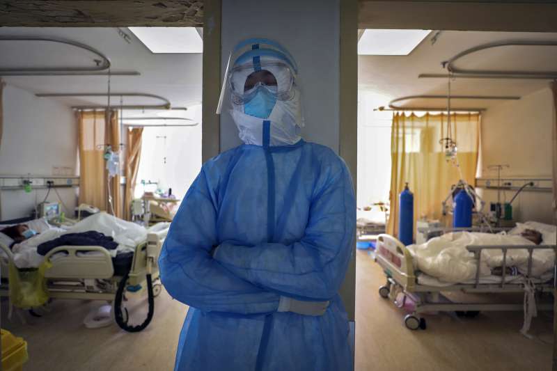 中國湖北省武漢市，身著全套保護裝束的醫護人員只能趁隙站著打瞌睡。新冠肺炎、武漢肺炎。（AP）