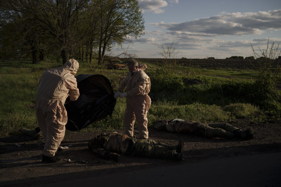 Emergency workers prepare to remove the bodies of Russian soldiers in the village of Vilkhivka, recently retaken by Ukrainian forces near Kharkiv, Ukraine, Monday, May 9, 2022. (AP Photo/Felipe Dana)