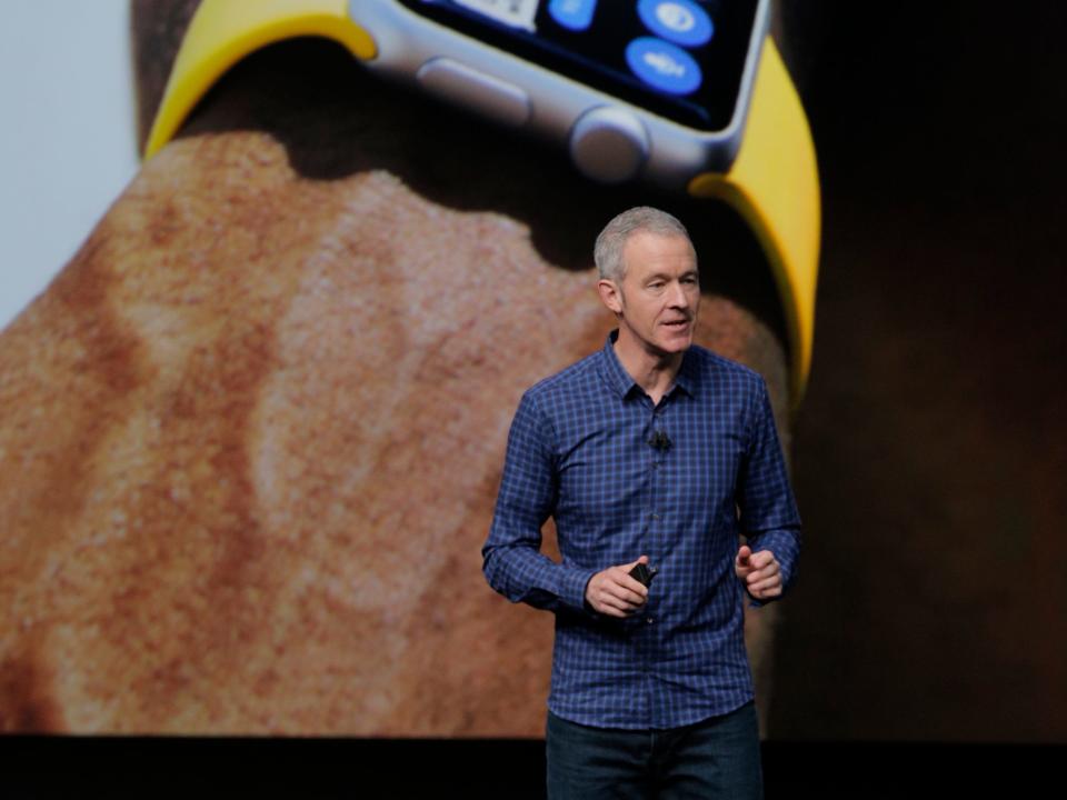 Jeff Williams with gray hair in a blue flannel button-up stands in front of a digital watch
