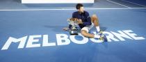 Serbia's Novak Djokovic sits on the court with the men's singles trophy after winning his final match against Britain's Andy Murray at the Australian Open tennis tournament at Melbourne Park, Australia, January 31, 2016. REUTERS/Issei Kato