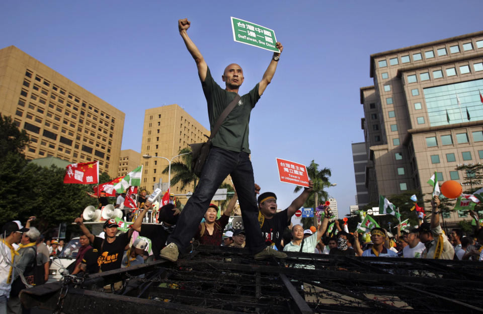 FILE - In this Nov. 6, 2008, file photo, pro-Taiwan supporters stand on top of police barricades and shout slogans in protest against the visit of China's top negotiator in Taipei, Taiwan. The residents of this self-governing island are supporting their president Tsai Ing-wen as she stands up to China’s calls for unification with the mainland. (AP Photo/Wally Santana, File)