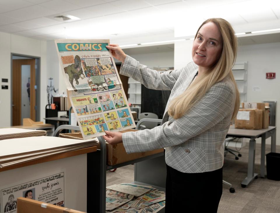 Sept. 15, 2023; Columbus, Oh., USA;  Jenny Robb, head curator of comics and cartoon art at the Billy Ireland Cartoon Library & Museum at Ohio State University, holds up a Sunday comics section from a newspaper featuring, "Calvin and Hobbes." 