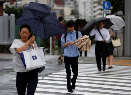 Passersby using umbrellas struggle against heavy rain and wind wind caused by Typhoon Faxai in Tokyo