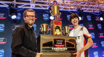 Dale Earnhardt Jr. and Casey Kirwan flank the championship trophy award to Kirwan for winning the eNASCAR iRacing championship.