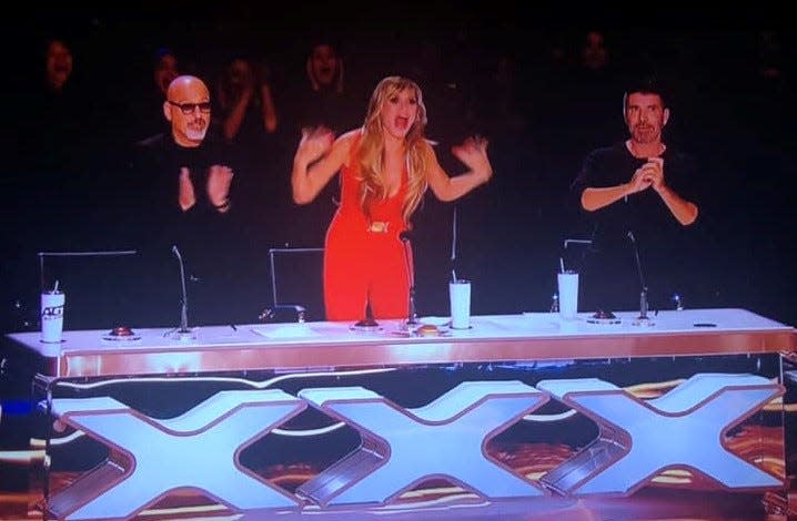 After Aerialist Aidan Bryant's AGT: All-Stars 2023 Finals performance, Heidi Klum expressed her excitement by screaming and vigorously waving her hands. From left to right, Howie Mandel, Heidi Klum and Simon Cowell.