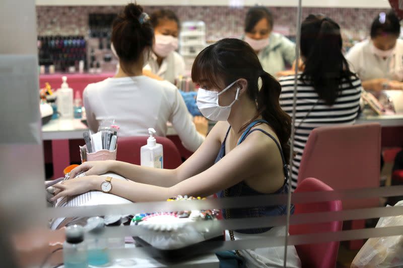 A woman wearing a protective mask against coronavirus makes is having her nails done in a shopping mall in Bangkok