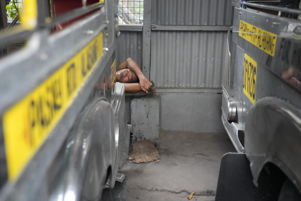 A man sleeps beside jeepneys waiting for passengers at a terminal in Pasay, Philippines Tuesday, Oct. 11, 2022. Many Filipino drivers complain that inflation, and especially the rising price of diesel, is forcing them to work more to get by. (AP Photo/Aaron Favila)
