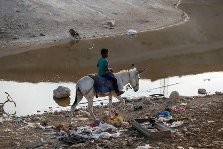 A boy rides a donkey past a wastewater pond in the Palestinian Bedouin village of Khan al-Ahmar that Israel plans to demolish, in the occupied West Bank October 2, 2018. REUTERS/Mohamad Torokman