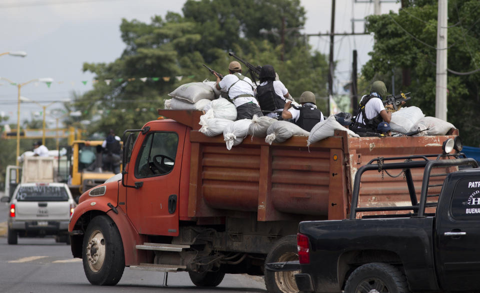 Men belonging to the Self-Defense Council of Michacan, (CAM), ride on a sandbag filled truck while trying to flush out alleged members of the Knights Templar drug cartel from the town of Nueva Italia, Mexico, Sunday Jan. 12, 2014. The vigilantes say they are liberating territory in the so-called Tierra Caliente and are aiming for the farming hub of Apatzingan, said to be the cartel's central command. Mexican military troops are staying outside the town and there are no federal police in sight. (AP Photo/Eduardo Verdugo)