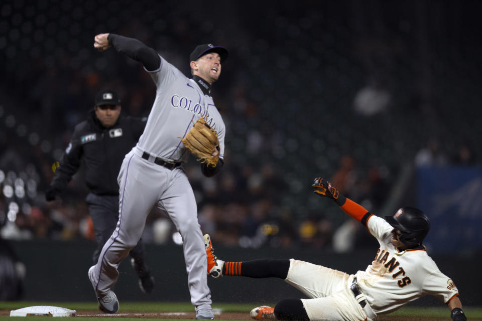 Colorado Rockies third baseman Ryan McMahon (24) throws over San Francisco Giants' Mauricio Dubón (1) to complete a double play during the seventh inning of a baseball game, Monday, May 9, 2022, in San Francisco. Wilmer Flores was out at first base. (AP Photo/D. Ross Cameron)