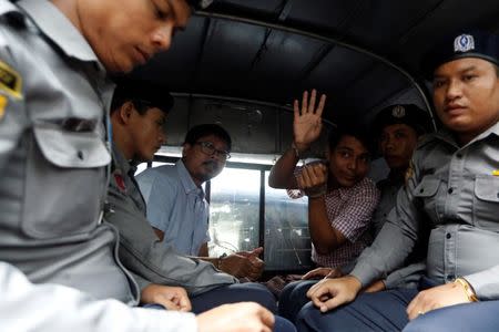 Detained Reuters journalist Wa Lone and Kyaw Soe Oo sit beside police officers as they leave Insein court in Yangon, Myanmar July 9, 2018. REUTERS/Ann Wang