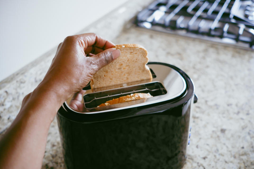 someone putting bread into a toaster