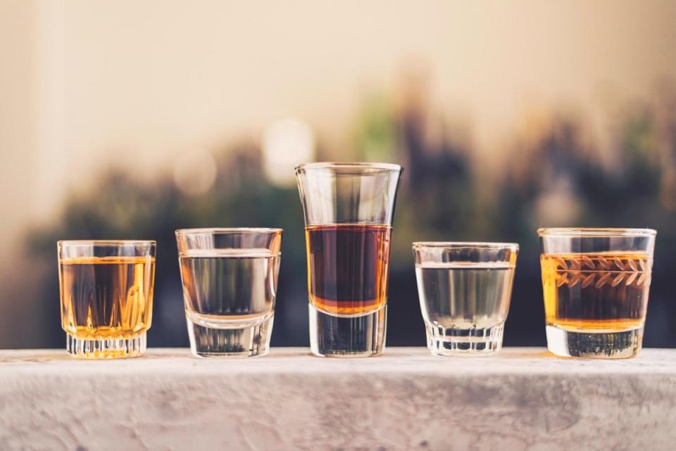 five clear shot glasses containing different alcohols