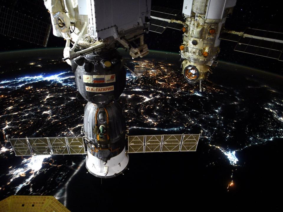 spaceships docked to the space station above nighttime earth